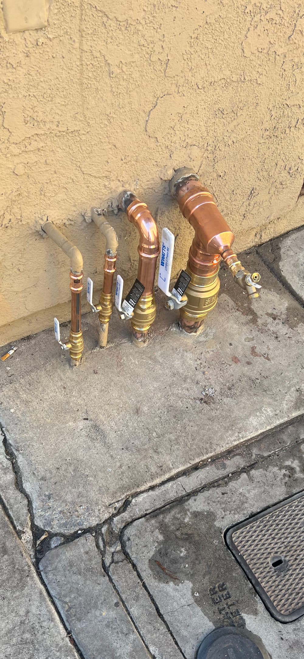 Copper plumbing valves and pipes installed on a concrete wall for water supply management.