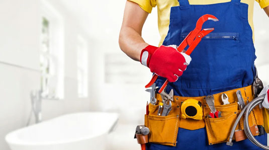 A person holding tools in their hands while wearing an apron.